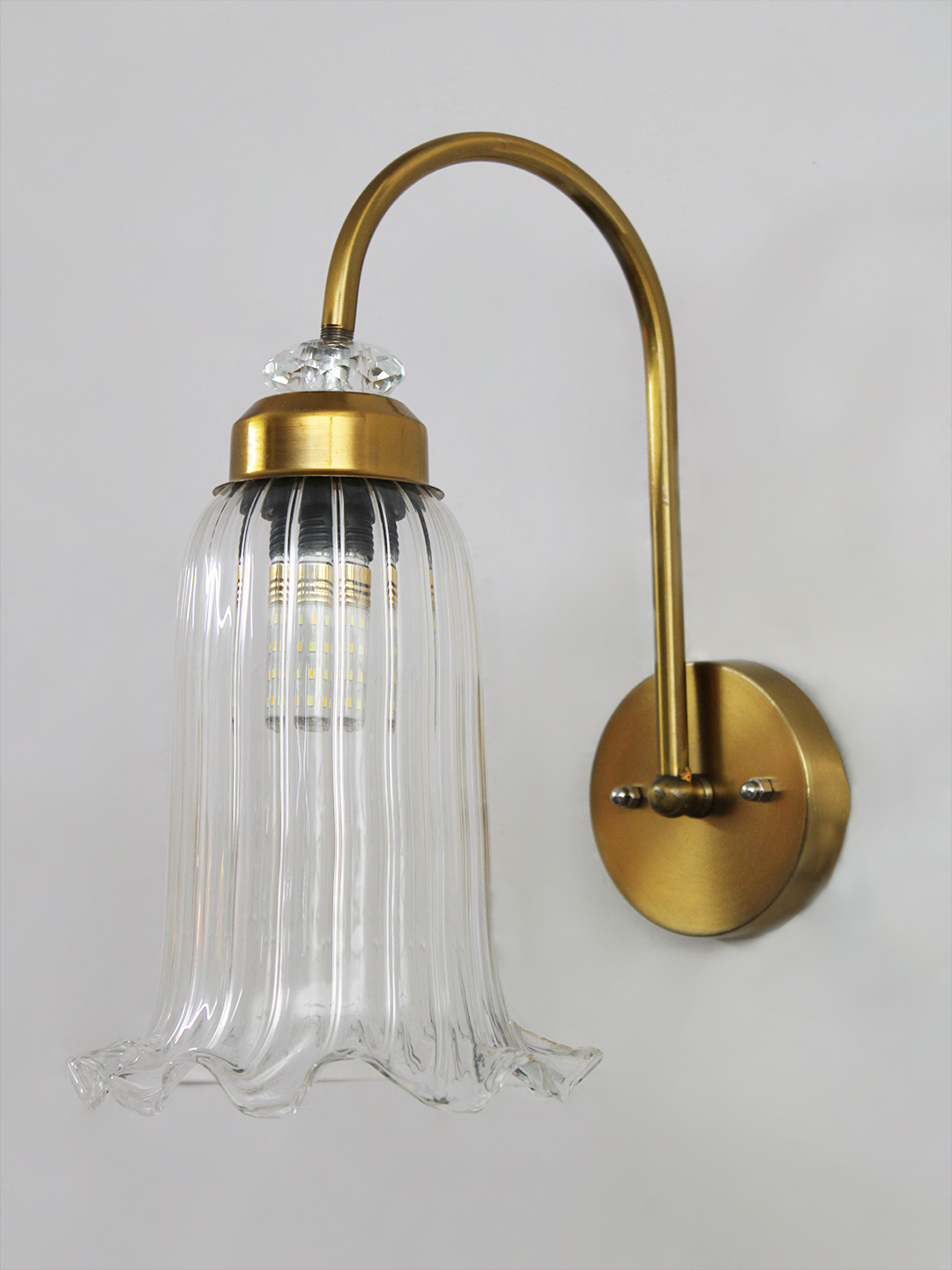 Antique Brass Fluted Glass Wall Sconce Antique brass fluted glass wall light with curved arm and decorative textured glass shade