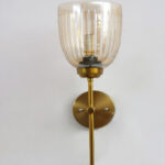 Antique brass wall light with amber ribbed glass shade and curved arm, shown with product dimensions.