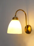Antique brass frosted glass wall light with curved arm and white shade, 11-inch decorative wall lamp for bedroom and living room.