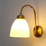 Antique brass frosted glass wall light with curved arm and white shade, 11-inch decorative wall lamp for bedroom and living room.