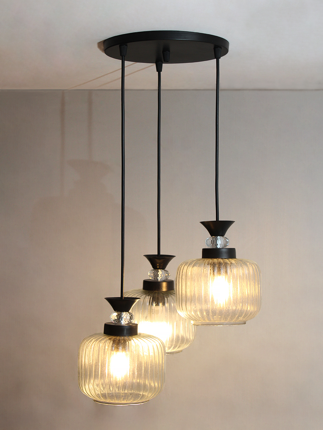 3-Light Clear Ribbed Glass Cluster Hanging Light Clear Ribbed Glass cluster hanging light with three pendant shades, black metal fittings, and adjustable drops for modern dining room and living room interiors.
