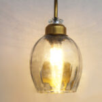 Antique brass smoked glass wall light with curved arm and round wall mount