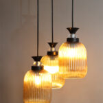 Decorative 3-Light cluster hanging light with three amber ribbed glass shades and black adjustable ceiling mount.