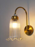 Antique brass fluted glass wall light with curved arm and decorative textured glass shade