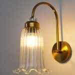 Antique brass fluted glass wall light with curved arm and decorative textured glass shade