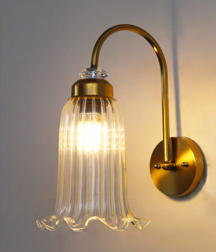 Antique brass fluted glass wall light with curved arm and decorative textured glass shade