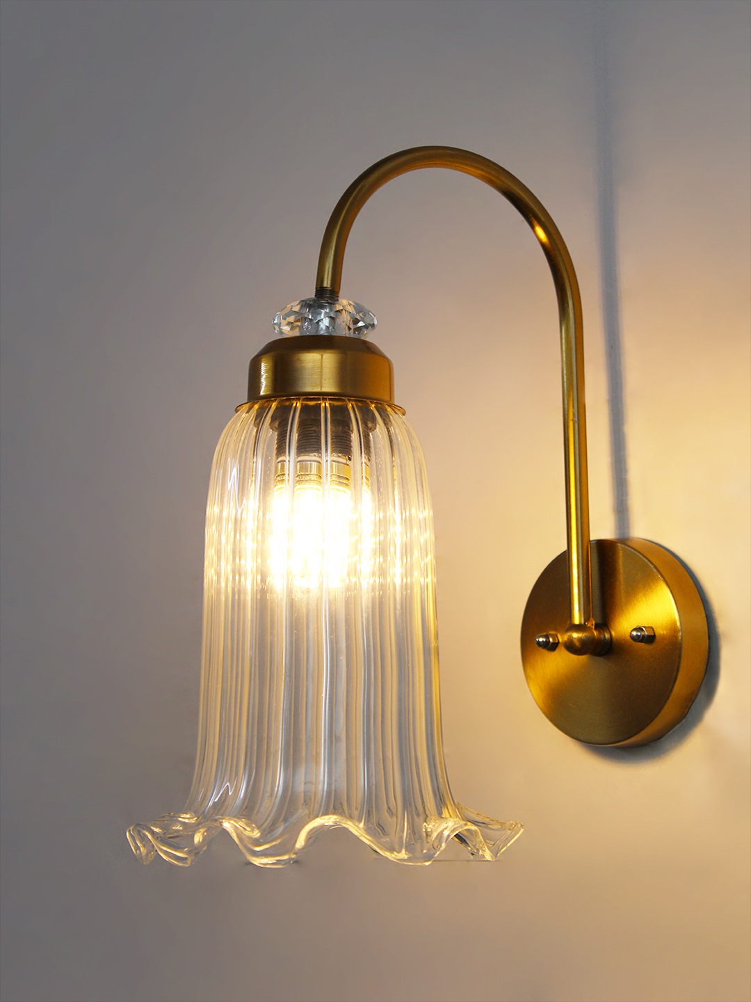 Antique Brass Fluted Glass Wall Sconce Antique brass fluted glass wall light with curved arm and decorative textured glass shade
