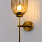 Antique brass wall light with amber ribbed glass shade and curved arm, shown with product dimensions.