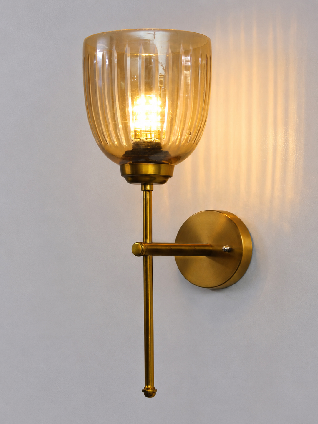 Antique Brass Fluted Glass Wall Sconce Antique brass wall light with amber ribbed glass shade and curved arm, shown with product dimensions.