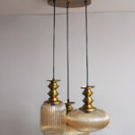 Ribbed Modern Ribbed Glass 3-light adjustable pendant ceiling light featuring three textured ribbed glass shades in different shapes, elegant golden metal holders, black hanging cords, 9-inch canopy, and up to 23-inch adjustable height.