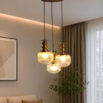 3-Light Ribbed Clear Glass adjustable pendant ceiling light with three 6-inch textured clear ribbed glass shades, decorative golden metal holders, black adjustable hanging cords, 9-inch circular canopy, and up to 23-inch adjustable height.