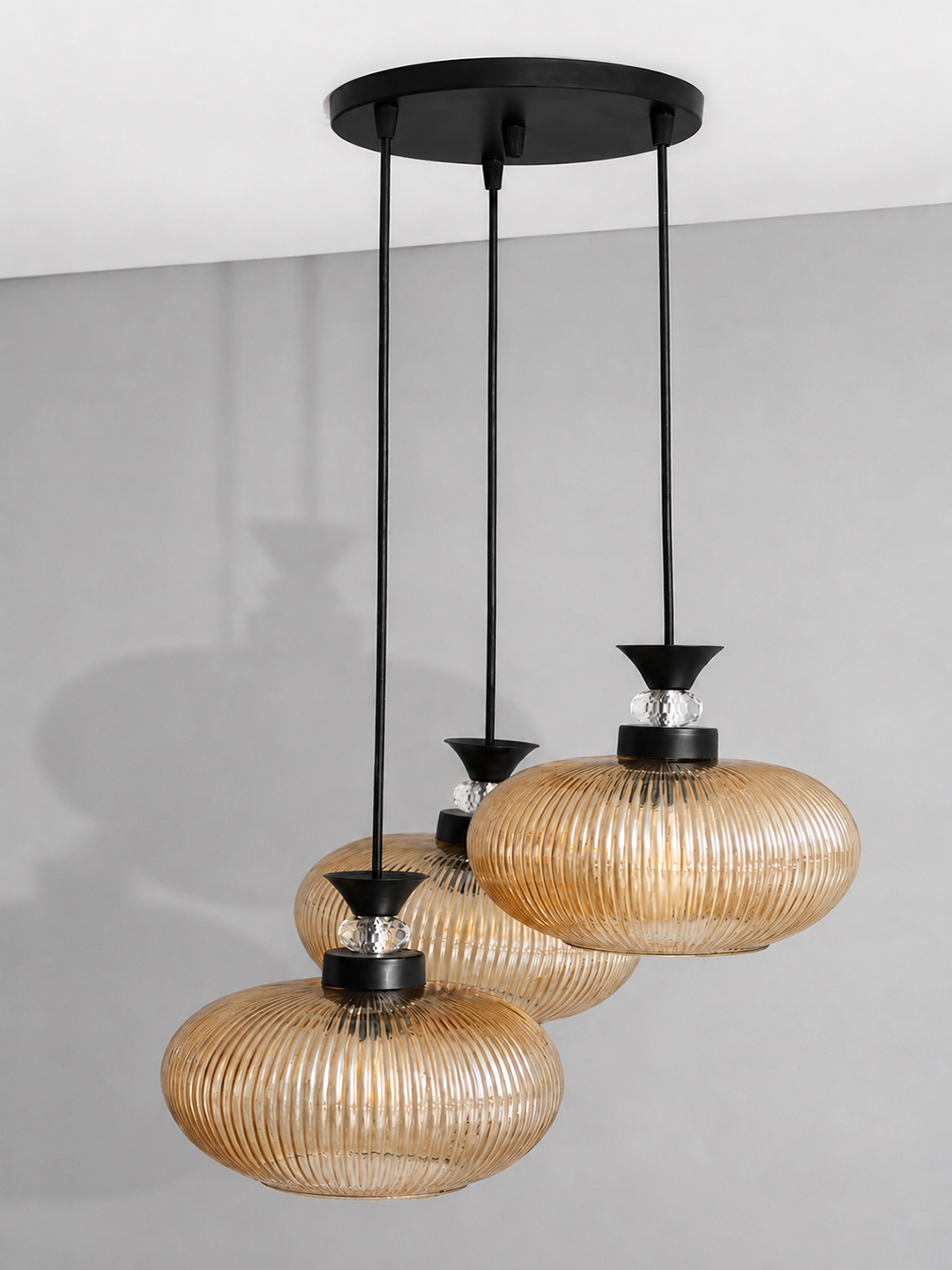 3-Light Amber Ribbed Glass Cluster Hanging Light Amber Ribbed Glass cluster hanging light with four textured glass pendant shades, black metal fittings, and layered design for modern interior lighting.