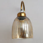 Antique brass wall light with amber ribbed glass shade and curved metal arm, shown with product dimensions.