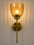 Antique brass wall light with amber ribbed glass shade and curved arm, shown with product dimensions.