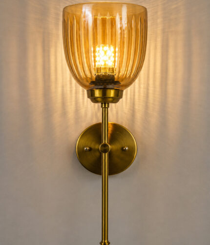 Antique brass wall light with amber ribbed glass shade and curved arm, shown with product dimensions.