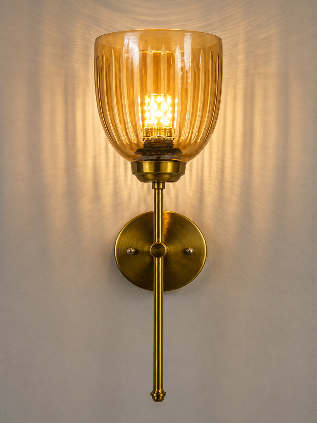 Amber Ribbed Glass Wall Sconce Antique brass wall light with amber ribbed glass shade and curved arm, shown with product dimensions.