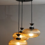 Amber Ribbed Glass cluster hanging light with four textured glass pendant shades, black metal fittings, and layered design for modern interior lighting.