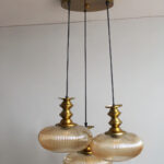 Ribbed Amber Kachori Glass 3-light adjustable pendant ceiling light with three rounded textured amber ribbed glass shades, elegant golden metal holders, 9-inch ceiling canopy, and 23-inch adjustable hanging cords.