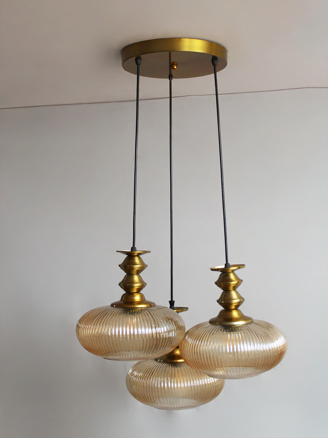 Ribbed Amber Kachori Glass Cluster Hanging Light Ribbed Amber Kachori Glass 3-light adjustable pendant ceiling light with three rounded textured amber ribbed glass shades, elegant golden metal holders, 9-inch ceiling canopy, and 23-inch adjustable hanging cords.