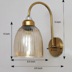 Antique brass wall light with amber ribbed glass shade and curved metal arm, shown with product dimensions.