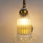 Antique brass fluted glass wall light with curved arm and decorative textured glass shade