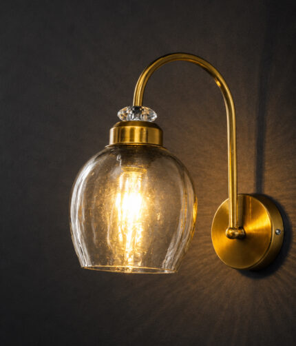 Antique brass smoked glass wall light with curved arm and round wall mount