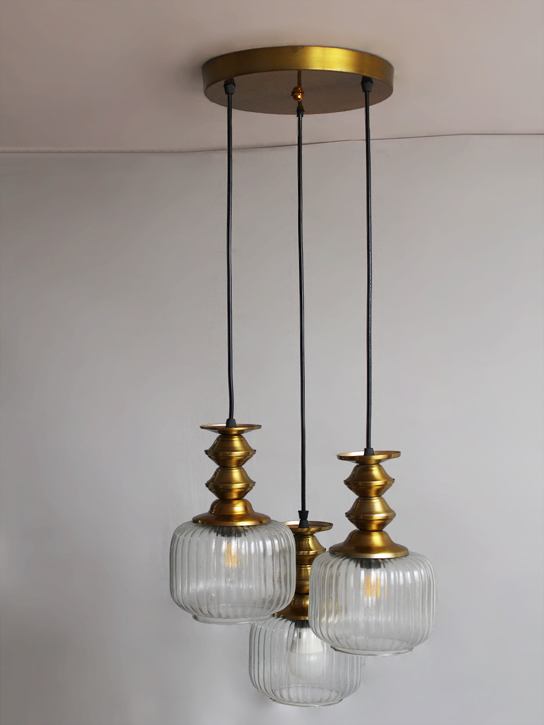 3-Light Ribbed Clear Glass Cluster Hanging Light 3-Light Ribbed Clear Glass adjustable pendant ceiling light with three 6-inch textured clear ribbed glass shades, decorative golden metal holders, black adjustable hanging cords, 9-inch circular canopy, and up to 23-inch adjustable height.