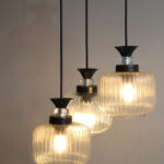 Clear Ribbed Glass cluster hanging light with three pendant shades, black metal fittings, and adjustable drops for modern dining room and living room interiors.
