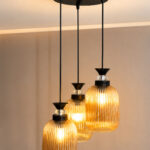 Decorative 3-Light cluster hanging light with three amber ribbed glass shades and black adjustable ceiling mount.