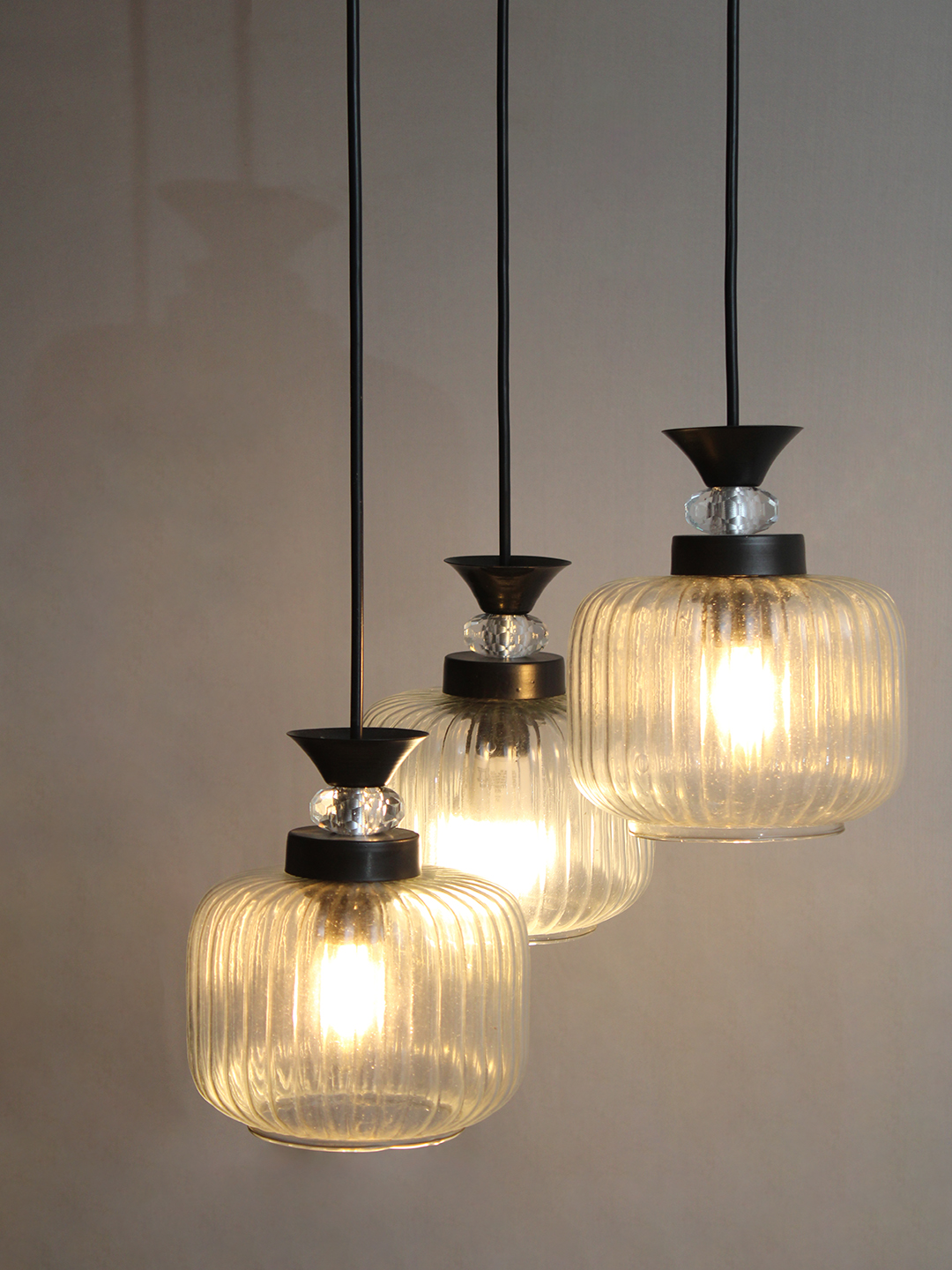3-Light Clear Ribbed Glass Cluster Hanging Light Clear Ribbed Glass cluster hanging light with three pendant shades, black metal fittings, and adjustable drops for modern dining room and living room interiors.
