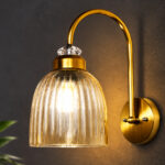 Antique brass wall light with amber ribbed glass shade and curved metal arm, shown with product dimensions.