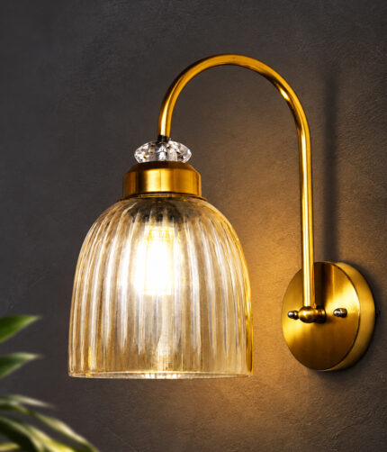 Antique brass wall light with amber ribbed glass shade and curved metal arm, shown with product dimensions.