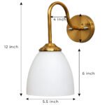 Antique brass wall sconce with curved arm and milky white bell-shaped glass shade.