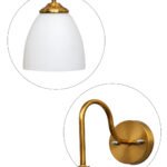 Antique brass wall sconce with curved arm and milky white bell-shaped glass shade.